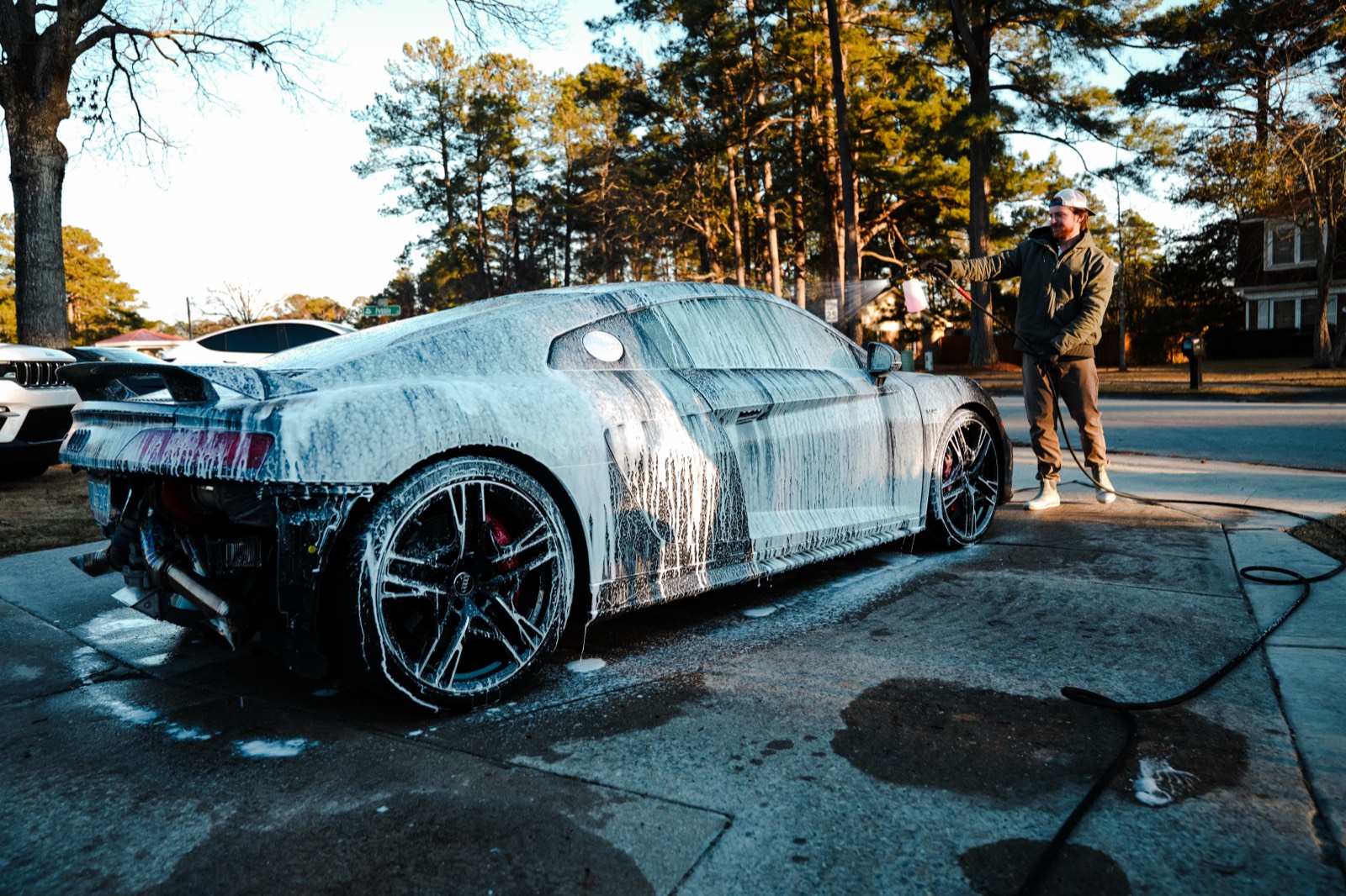 Audi R8 coated in snow foam during an exterior detail at golden hour