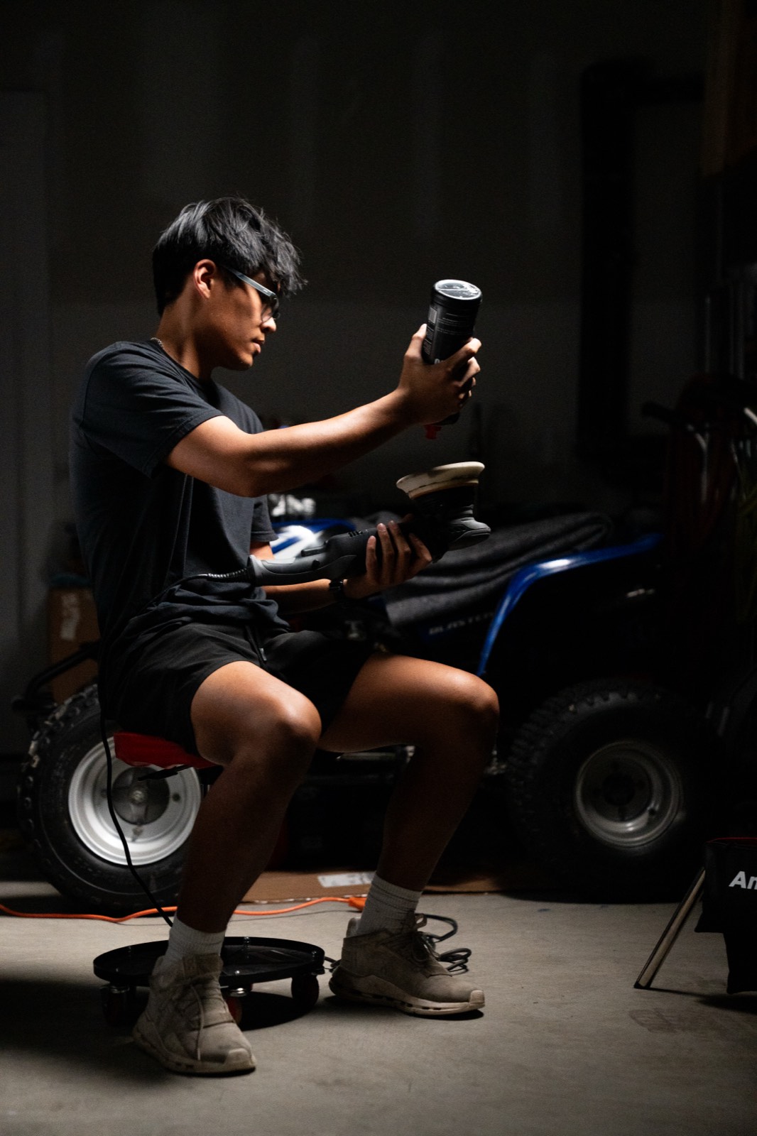 Detailer preparing a polishing pad and dual-action polisher in the garage