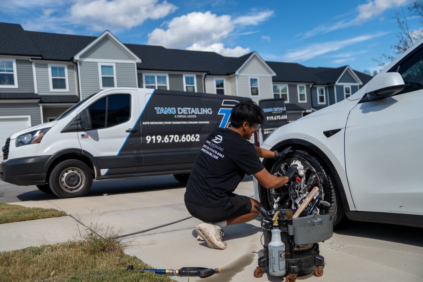 Mobile detailing service van parked beside a Tesla during an on-site wheel detail