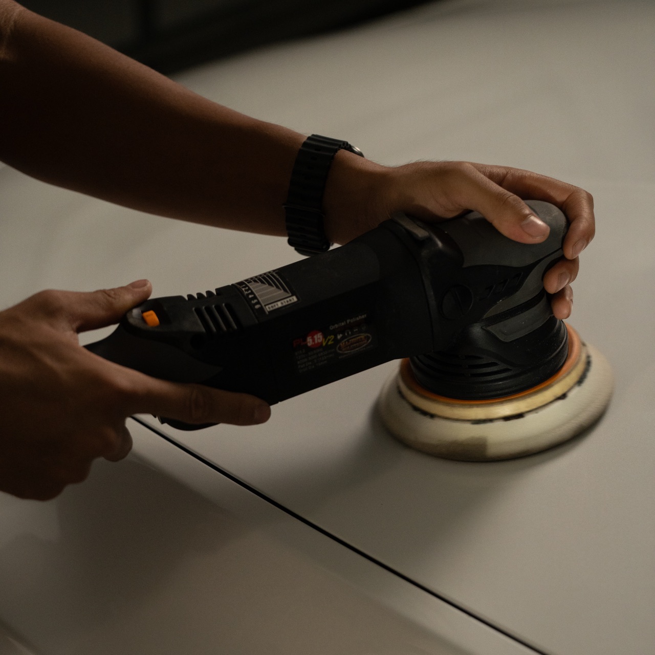 Detailer running a dual-action polisher for paint correction
