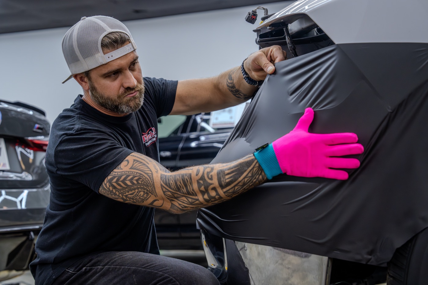 Installer applying black paint protection film to a panel